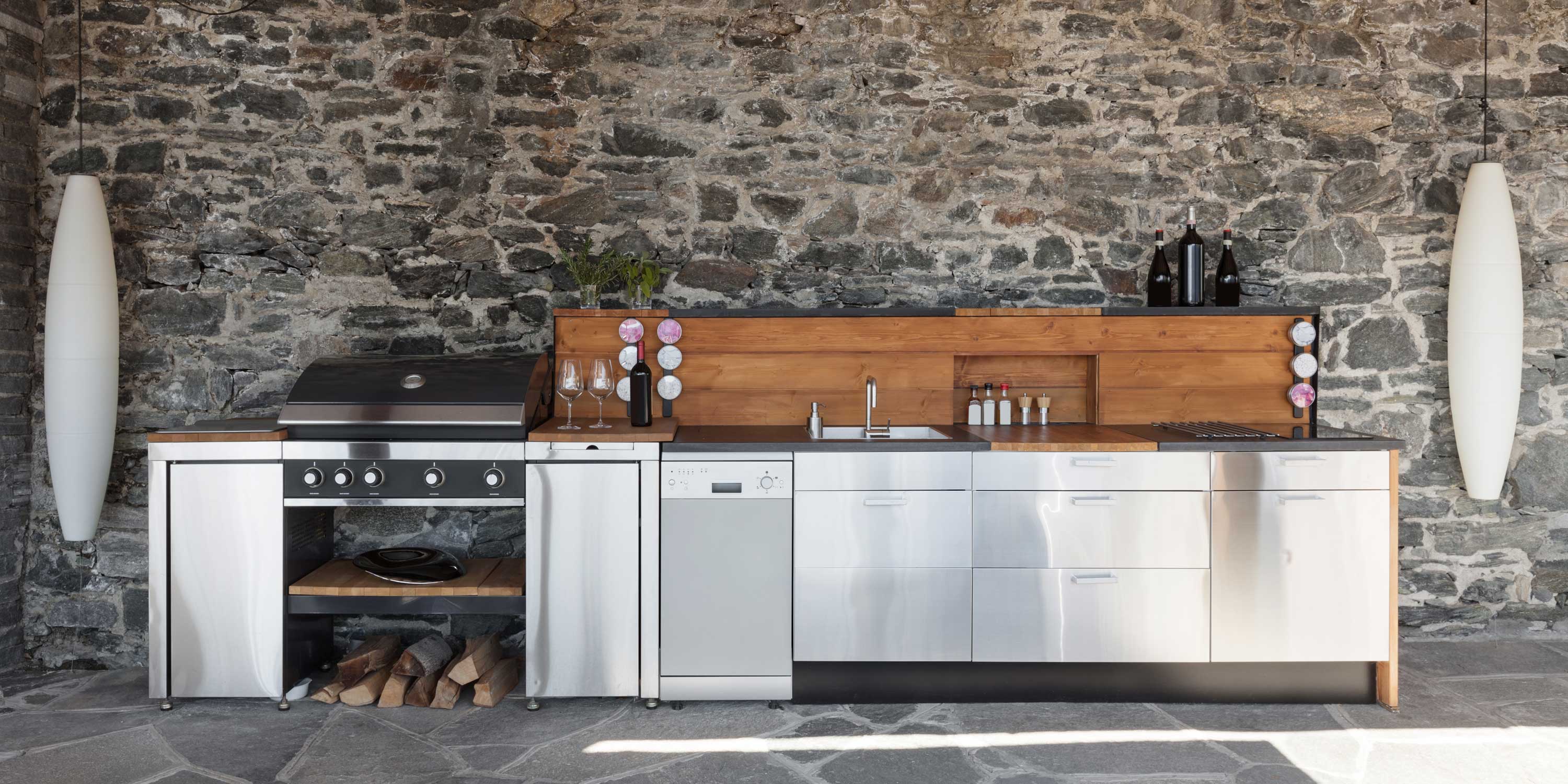 outdoor kitchen with stone walls and stainless steel appliances