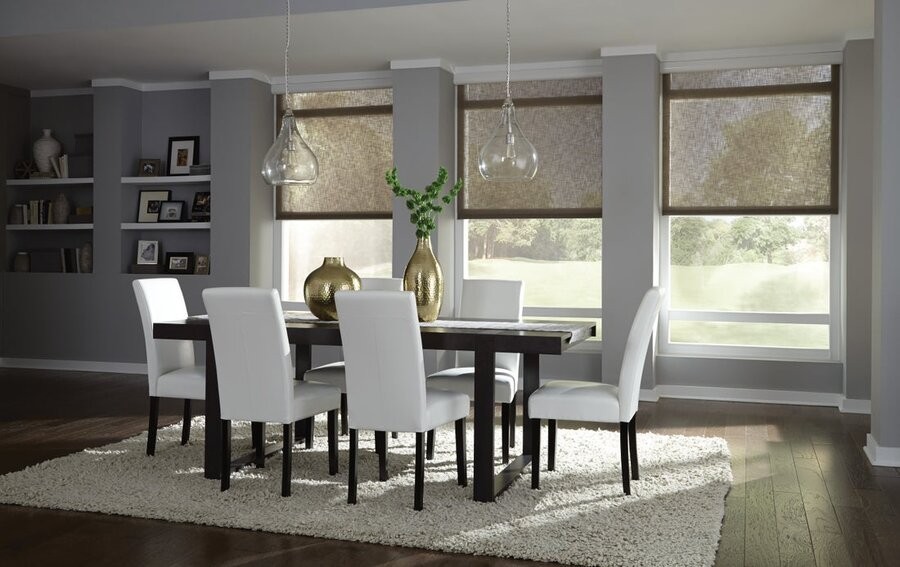 A dining room area with three windows featuring motorized shades.